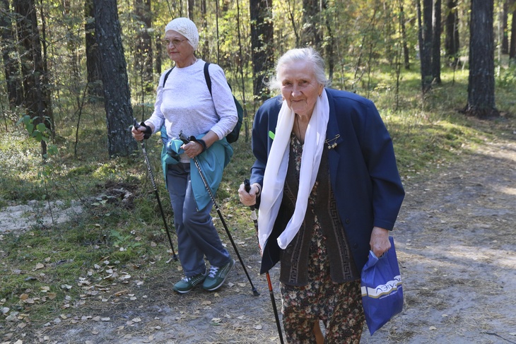 Пожилые женщины занимаются скандинавской ходьбой