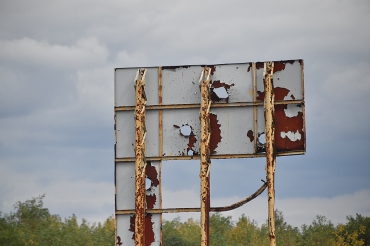 Пробитый снарядами рекламный щит в Луганске